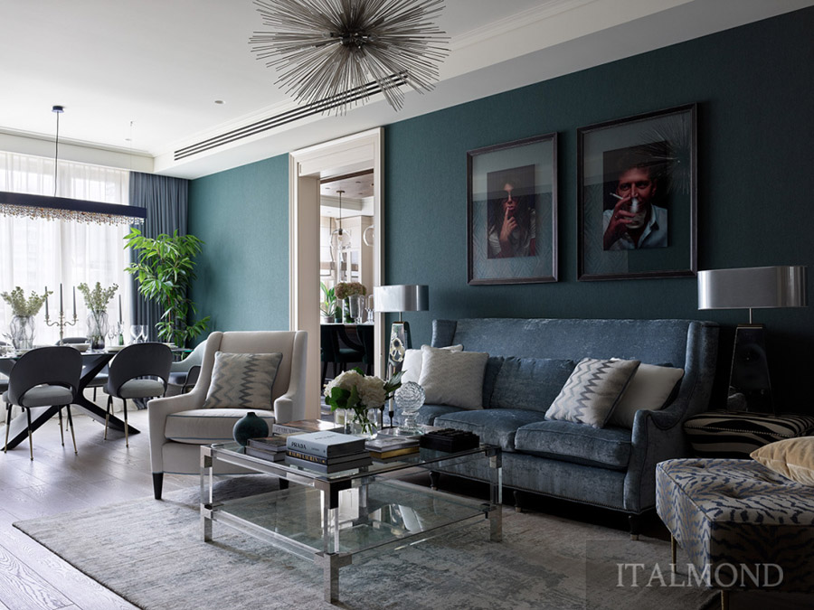 Гостиная с синим бархатным диваном, стеклянным столом и картинами