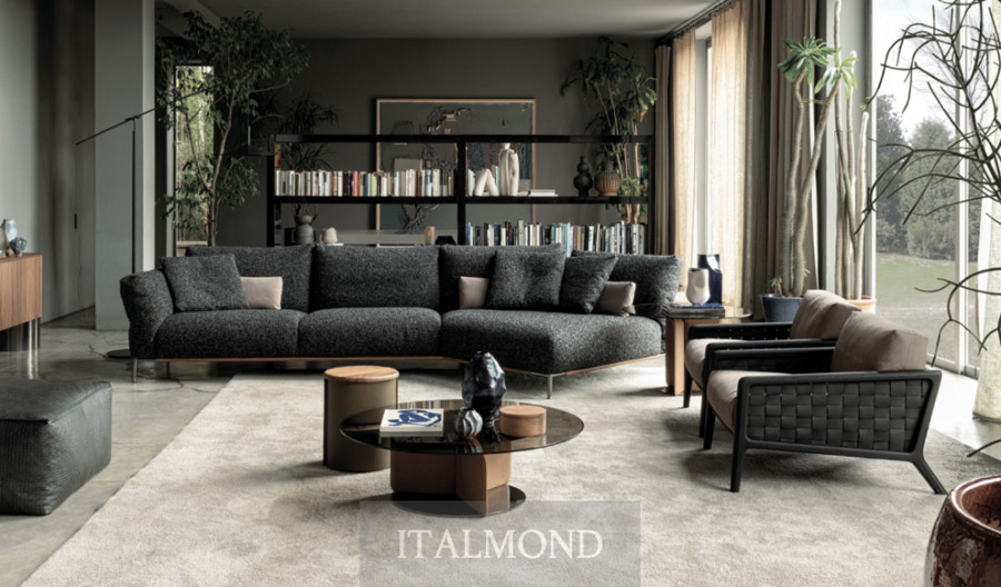 Гостиная с большим темным угловым диваном, ковром и растениями