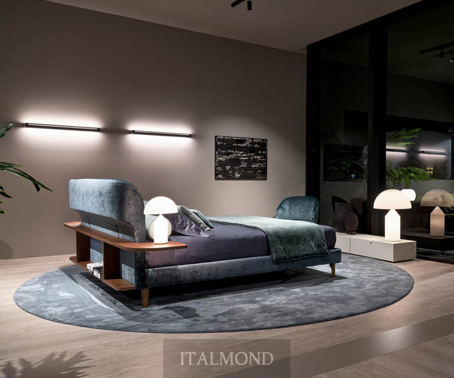 Спальня с синим бархатным изголовьем, круглым ковром и лампами