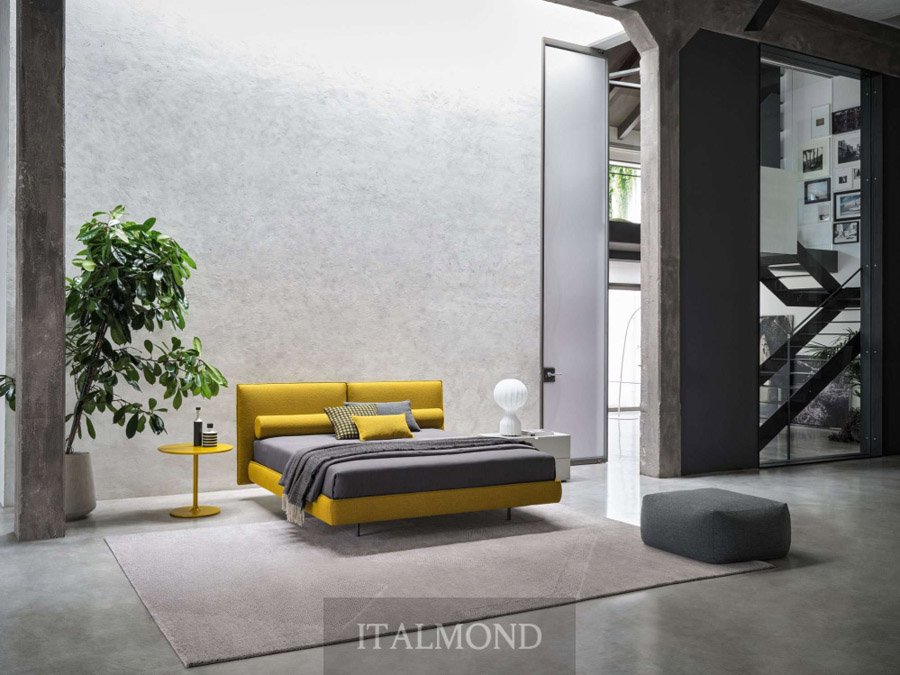 Спальня в стиле лофт с яркой желтой кроватью и бетонными колоннами