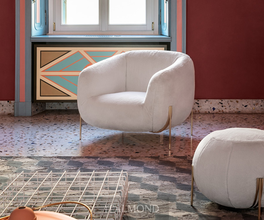 Пушистое белое кресло с золотыми ножками на фоне красной стены