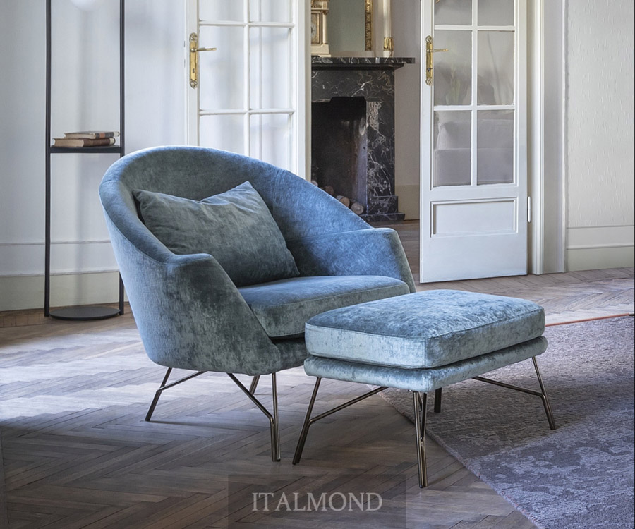 Голубое бархатное кресло с пуфом в классической гостиной с камином