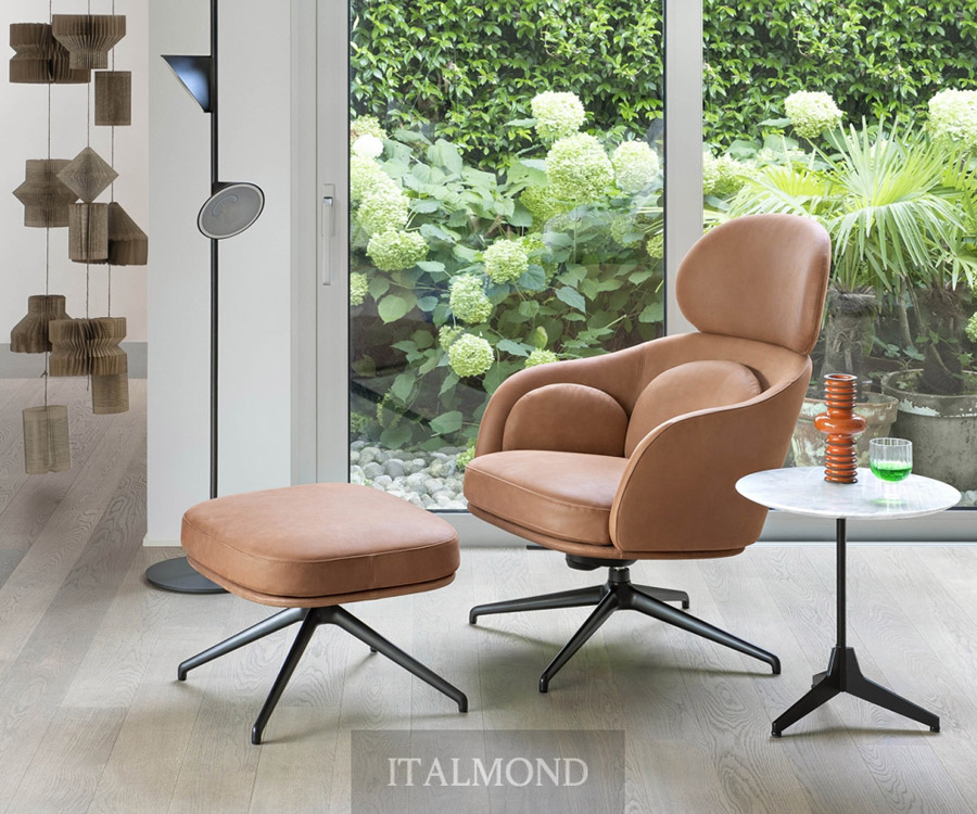 Коричневое кожаное кресло-реклайнер с пуфом у окна с зеленью